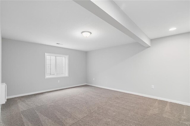 spare room featuring beamed ceiling and carpet flooring