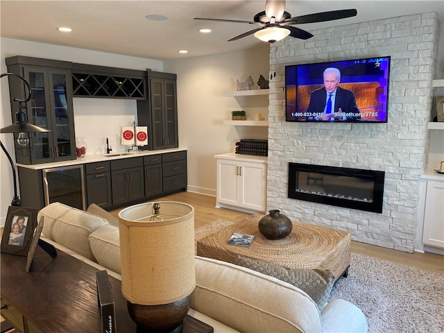 16445 S Elmridge St, Olathe, KS 66062 - living room with light wood-type flooring, wet bar, a large fireplace, recessed lighting, and a ceiling fan