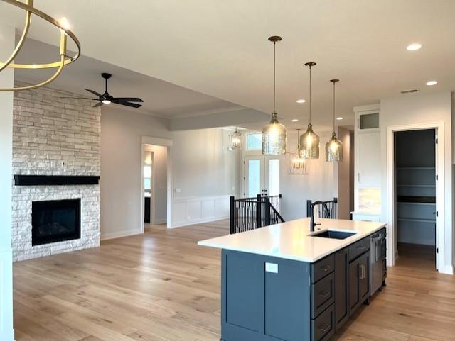 16445 S Elmridge St, Olathe, KS 66062 - kitchen featuring light countertops, a kitchen island with sink, ceiling fan, light wood finished floors, and a sink