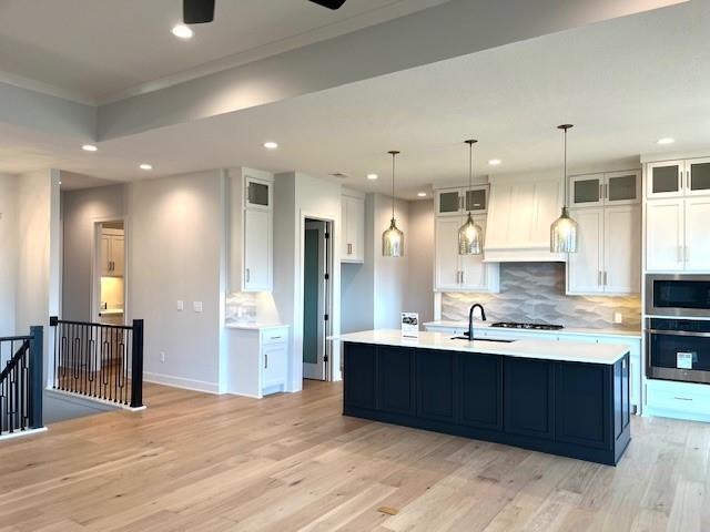 16445 S Elmridge St, Olathe, KS 66062 - kitchen featuring custom range hood, light wood-type flooring, white cabinetry, backsplash, and appliances with stainless steel finishes