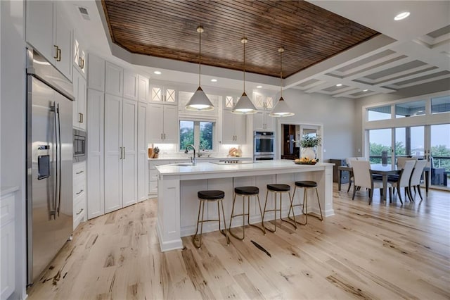 kitchen featuring built in appliances, decorative light fixtures, white cabinets, and a center island