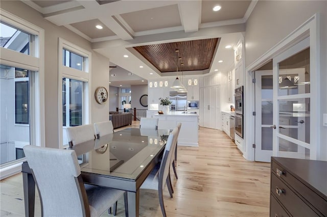 dining room with coffered ceiling, light hardwood / wood-style flooring, beamed ceiling, and ornamental molding