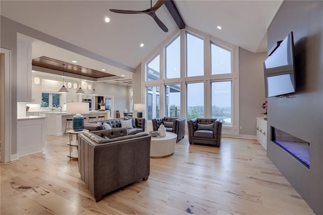 living room featuring light hardwood / wood-style flooring, sink, beamed ceiling, ceiling fan, and high vaulted ceiling