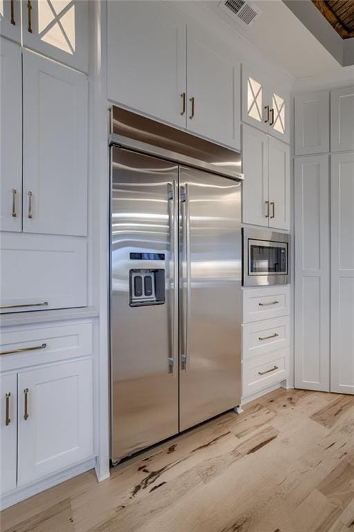 kitchen with built in appliances, white cabinetry, and light wood-type flooring