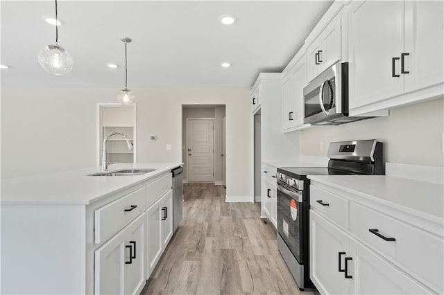 kitchen with appliances with stainless steel finishes, light countertops, a sink, and white cabinetry