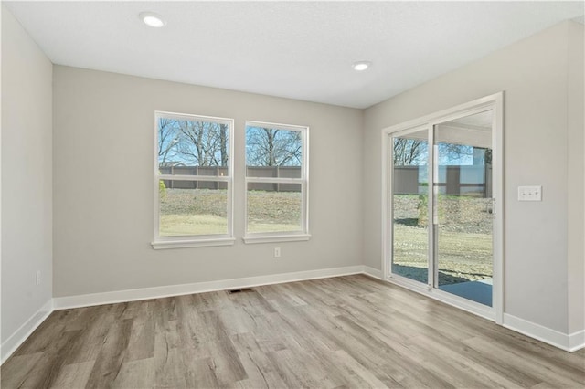 empty room with wood finished floors, visible vents, and baseboards