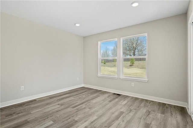 spare room featuring recessed lighting, wood finished floors, and baseboards