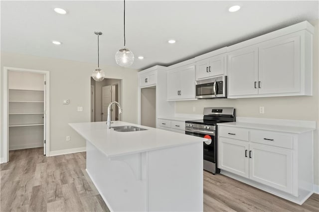 kitchen featuring appliances with stainless steel finishes, light wood-type flooring, a kitchen island with sink, and a sink