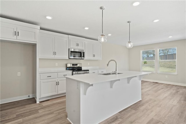 kitchen featuring stainless steel appliances, sink, pendant lighting, a center island with sink, and white cabinetry