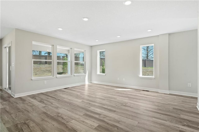 spare room with baseboards, wood finished floors, and recessed lighting