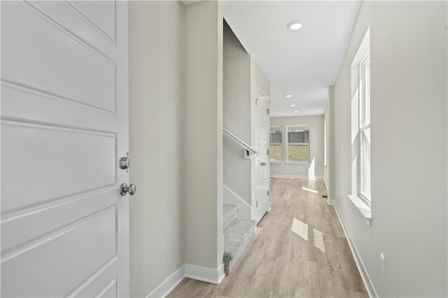 hallway with baseboards, stairway, recessed lighting, and light wood-style floors