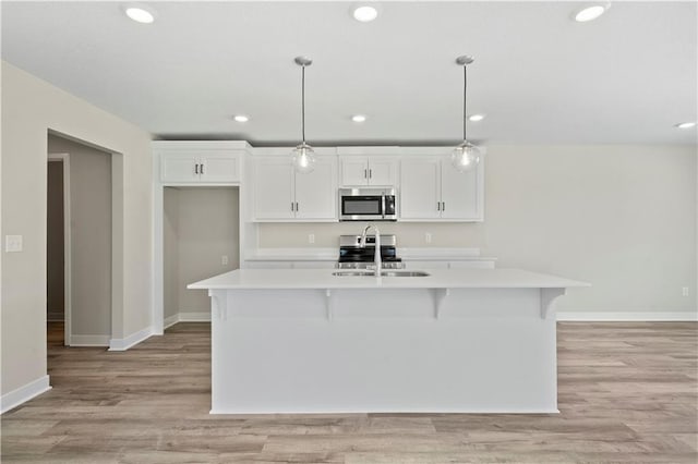 kitchen with white cabinets, stainless steel appliances, a sink, and light countertops