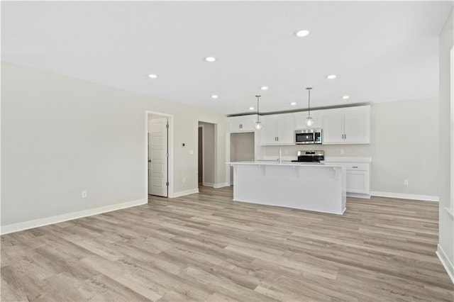 kitchen with baseboards, white cabinets, light wood-style flooring, stainless steel appliances, and recessed lighting