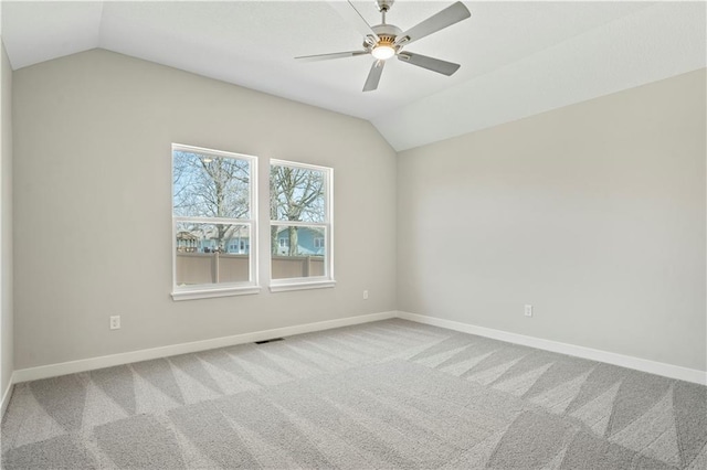 carpeted spare room with vaulted ceiling, ceiling fan, visible vents, and baseboards