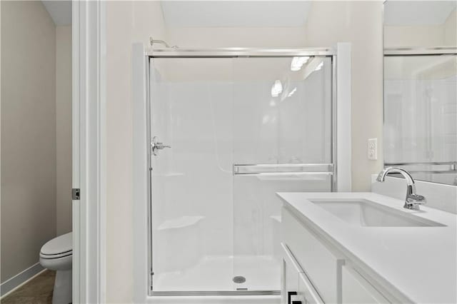 full bathroom featuring baseboards, a shower stall, toilet, and vanity