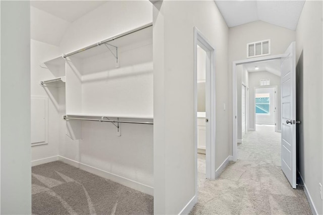 walk in closet featuring visible vents, vaulted ceiling, and carpet flooring