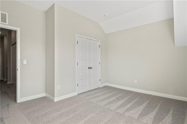 unfurnished bedroom featuring lofted ceiling, carpet, and baseboards