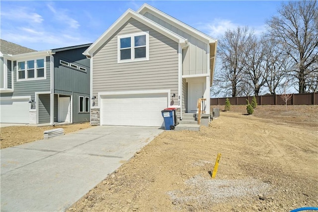 view of front of home with driveway, board and batten siding, an attached garage, and fence