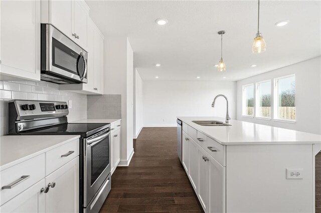 kitchen featuring appliances with stainless steel finishes, tasteful backsplash, sink, an island with sink, and dark hardwood / wood-style flooring