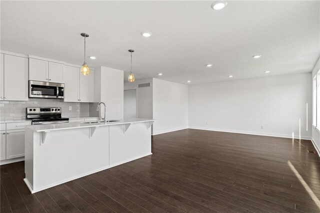 kitchen with white cabinets, decorative backsplash, dark wood-type flooring, and stainless steel appliances