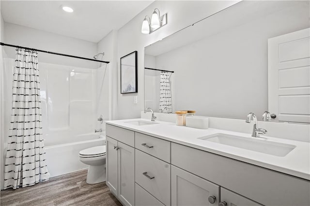 408 Woodview Dr, Raymore, MO 64083 - bathroom with wood finished floors, toilet, double vanity, shower / tub combo, and recessed lighting