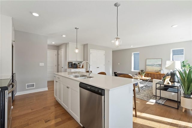 kitchen featuring sink, light hardwood / wood-style flooring, a kitchen island with sink, stainless steel dishwasher, and white cabinetry