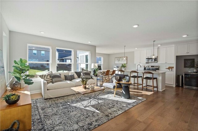 living room featuring beverage cooler, dark wood-type flooring, plenty of natural light, and sink