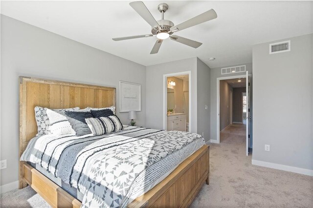 bedroom with ceiling fan, light colored carpet, and ensuite bathroom