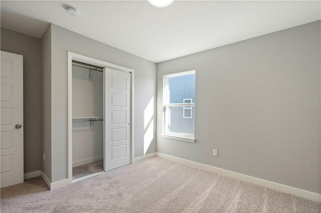 unfurnished bedroom with a closet, carpet flooring, and baseboards