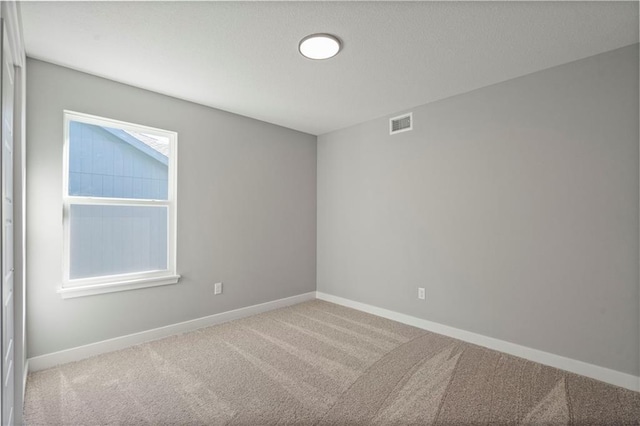 empty room with carpet floors, visible vents, and baseboards