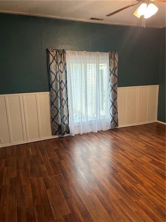 empty room featuring dark wood-type flooring, a textured ceiling, and ceiling fan