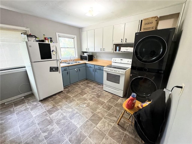 kitchen featuring white appliances, sink, stacked washer / dryer, white cabinets, and gray cabinets