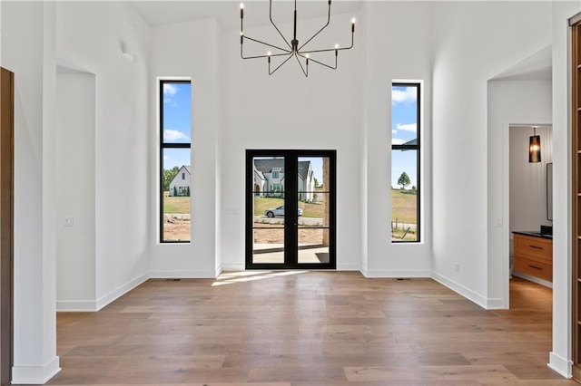 foyer featuring a towering ceiling, a notable chandelier, and light wood-type flooring