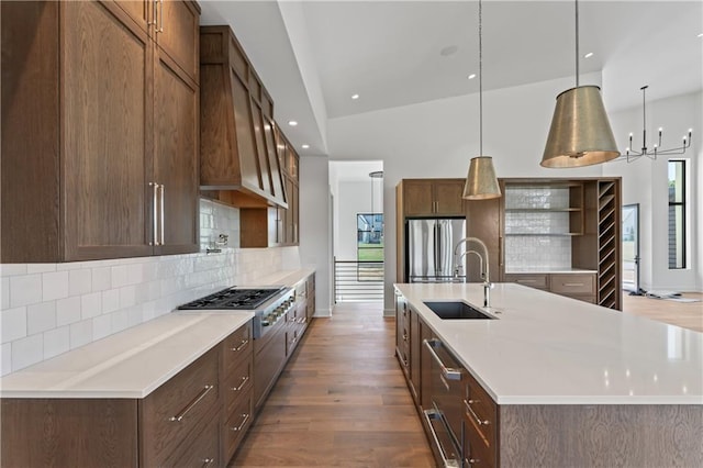 kitchen with hardwood / wood-style floors, vaulted ceiling, sink, hanging light fixtures, and appliances with stainless steel finishes