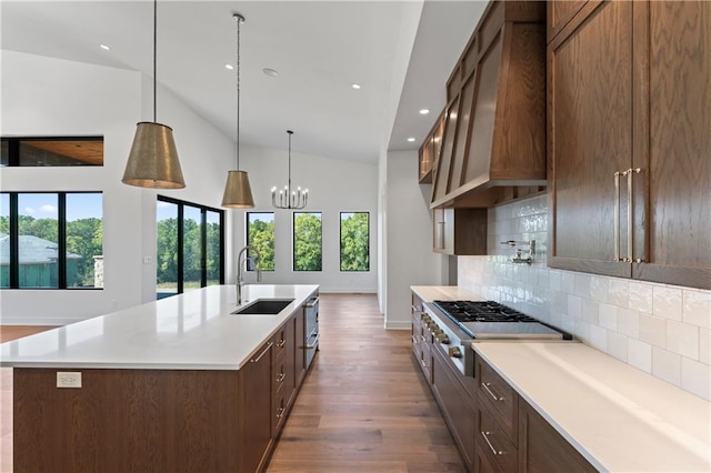 kitchen with stainless steel gas cooktop, dark wood-type flooring, a center island with sink, sink, and backsplash