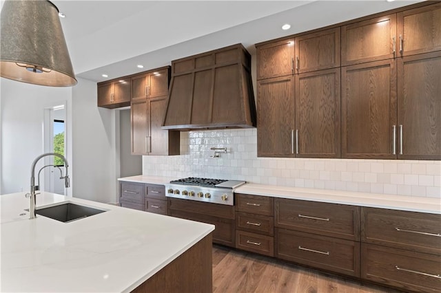 kitchen with decorative backsplash, premium range hood, sink, dark hardwood / wood-style flooring, and stainless steel gas stovetop