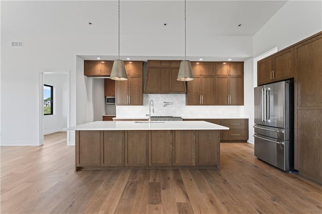 kitchen featuring stainless steel appliances, light hardwood / wood-style floors, and decorative light fixtures