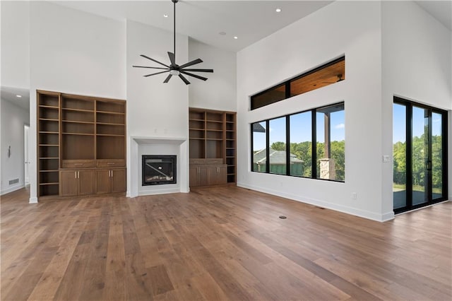 unfurnished living room with high vaulted ceiling, light hardwood / wood-style flooring, and ceiling fan