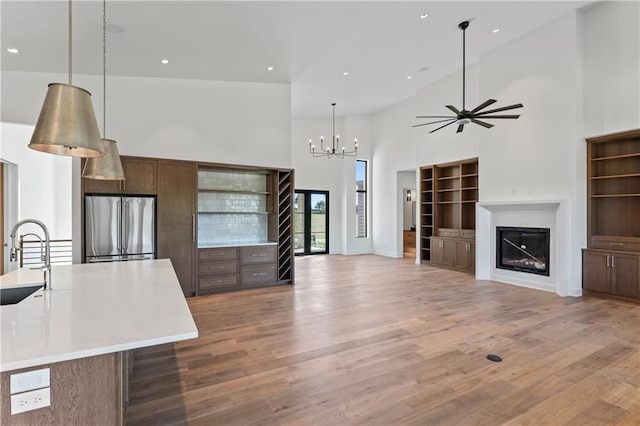 kitchen featuring pendant lighting, stainless steel fridge, a large island with sink, high vaulted ceiling, and hardwood / wood-style floors