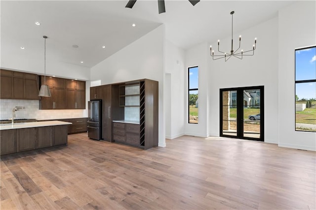 kitchen with stainless steel fridge, pendant lighting, high vaulted ceiling, and light hardwood / wood-style floors