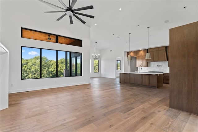 kitchen featuring wood-type flooring, ceiling fan with notable chandelier, high vaulted ceiling, and premium range hood