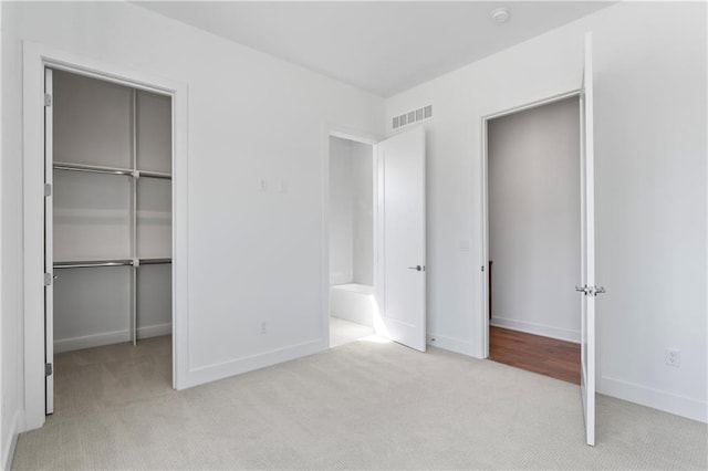 unfurnished bedroom with a closet and light colored carpet