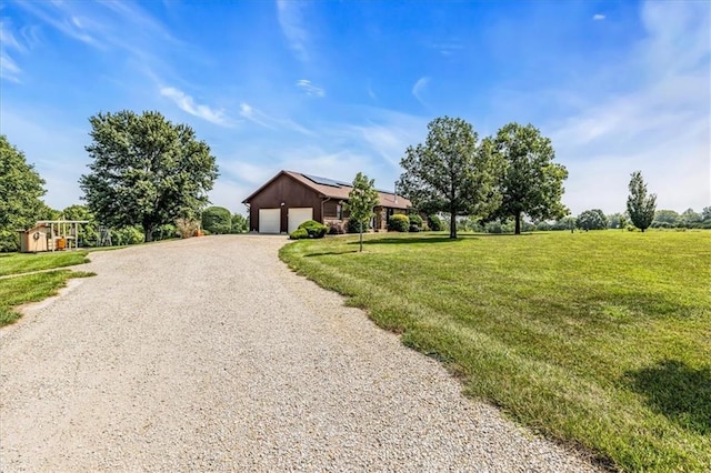 view of front of house with gravel driveway, a garage, and a front lawn