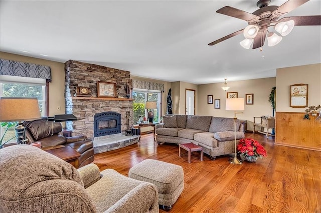 living area with a fireplace, a ceiling fan, and wood finished floors