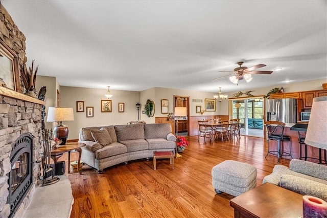 living area featuring light wood-style floors, a stone fireplace, and a ceiling fan