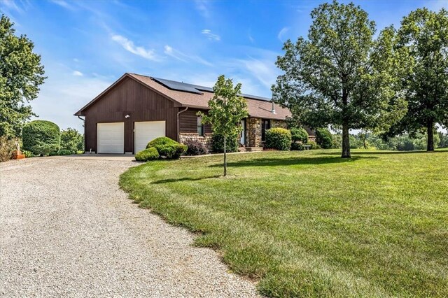 ranch-style house with a front yard, solar panels, and a garage