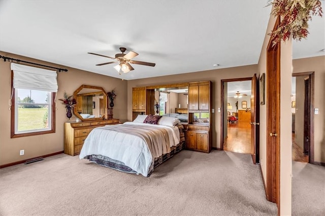 bedroom with a ceiling fan, light carpet, and baseboards