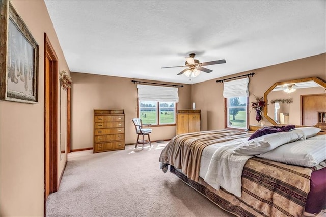 bedroom featuring a textured ceiling, baseboards, a ceiling fan, and light colored carpet