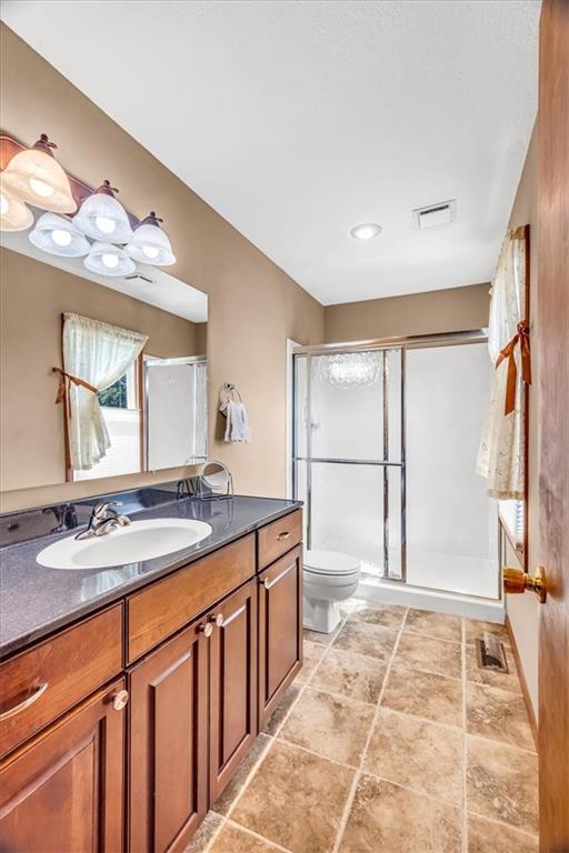 bathroom featuring vanity, toilet, and a shower with door