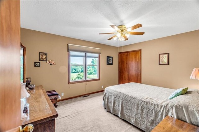 carpeted bedroom featuring ceiling fan and a textured ceiling